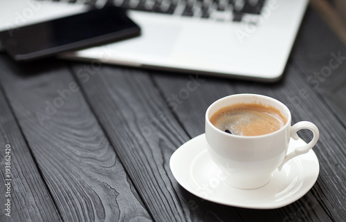 Coffee Cup on the white table on blurred laptop background for Business Concept.