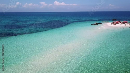 Aerial view of beautiful sand tropical island with white sand beach and tourists. White sand island. Seascape: ocean and beautiful beach paradise. Zanzibar, Tanzania. 4K video. Travel concept