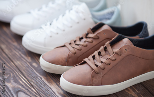 Various pairs of colorful sneakers laid on the wooden floor background