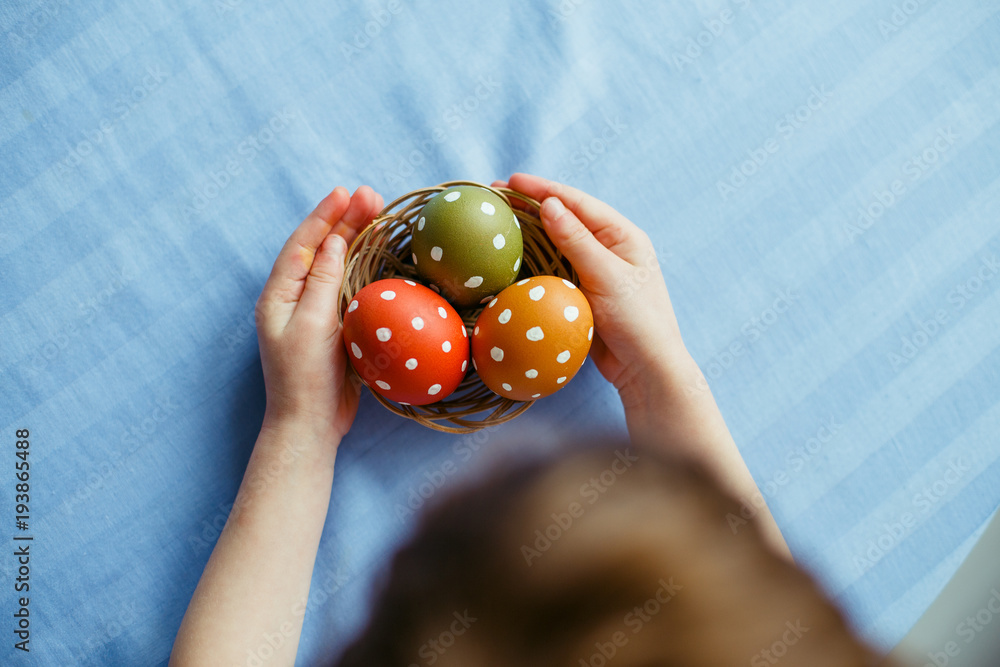 Close up of child holding colorful Easter egg with dots on a blue background Close up of child holding colorful Easter egg with dots on a blue background
