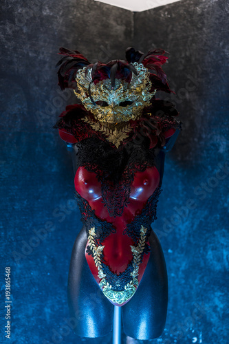 Masquerade Party Venetian red, mask and red corset with pieces of gold and black lace fabrics on metal breastplate. handmade piea for parties or costume meetings photo