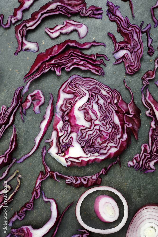 Obraz premium Arrangement of colorful red cabbage and red onion on slate table