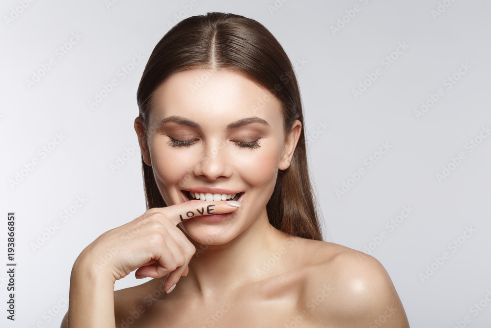 Portrait of sensual young woman keeping finger near her lips and smiling. Her eyes are closed with fondness. Isolated. Love concept Portrait of sensual young woman keeping finger near her lips and smiling. Her eyes are closed with fondness. Isolated. Love concept