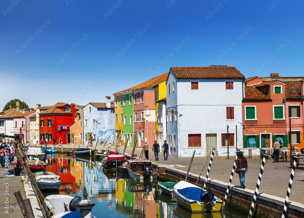 Urban landscape on the island of Burano with colorful buildings and tourists on the streets, Venice, Italy