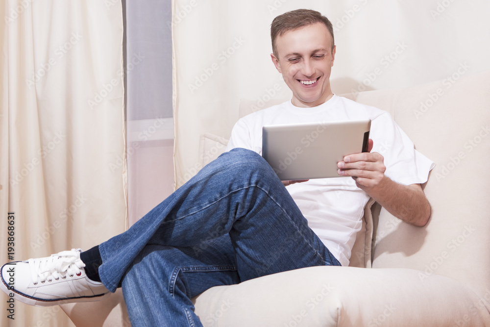 Smiling Caucasian Man with Tablet Computer on Couch. Posing in Home Environment. Smiling Caucasian Man with Tablet Computer on Couch. Posing in Home Environment.