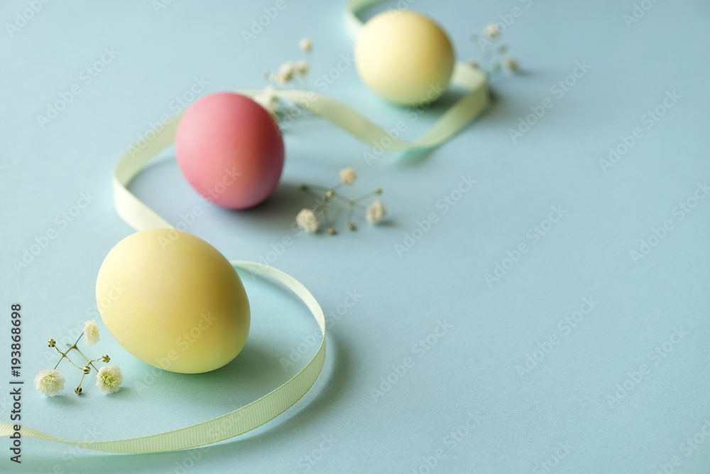 Different pastel color Easter eggs laid and arranged in beautiful composition with white wildflowers. Greeting card with copy text space.