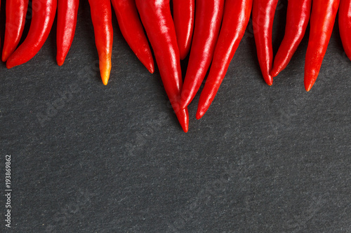 Slate background with red hot chilli peppers.