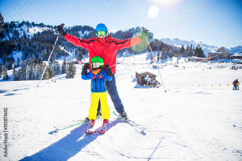 Little boy having fun with his attractive father during skiing in Alps.