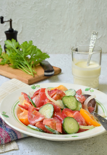 Vegetarian healthy salad with fresh ripe summer vegetables  tomato  cucumber  pepper and onion on light wooden background.