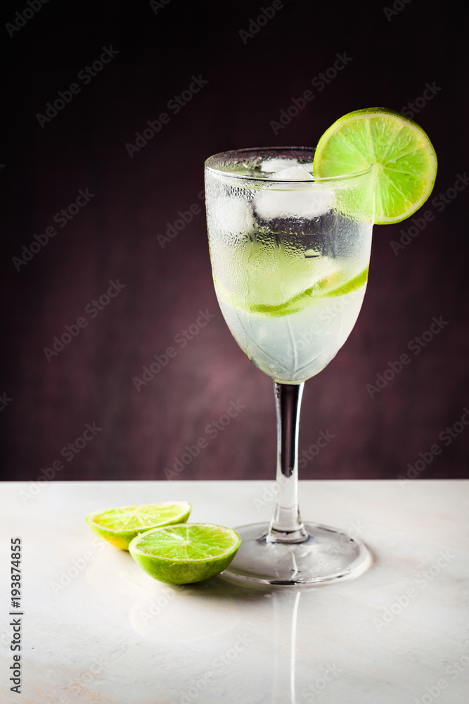 Cup with lemonade and a slice of lemon on a white table on a dark background