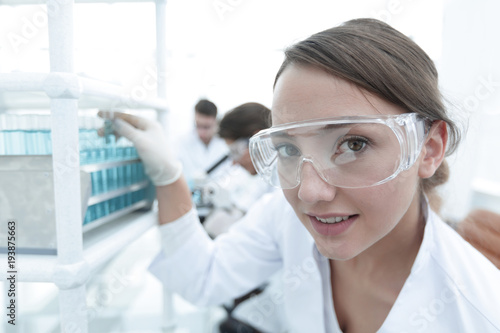 Young woman scientist in protective glasses holding test tubes