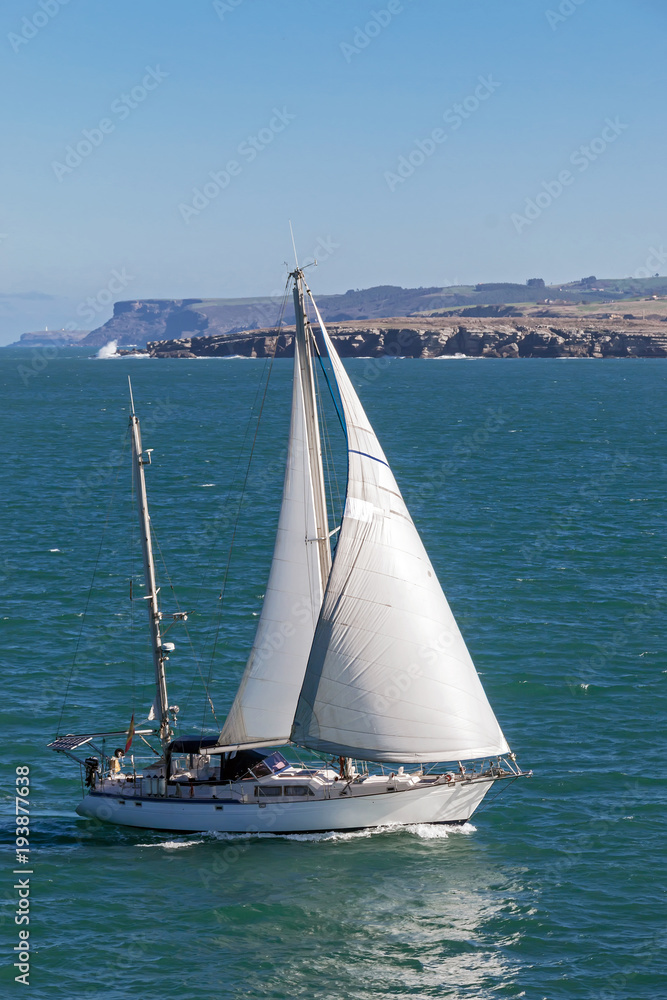 Fototapeta premium White small sailboat at peaceful clear sea scene under sunlight