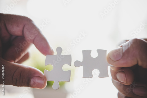 two hands trying to connect couple puzzle piece. one part of whole. symbol of association and connection. business strategy