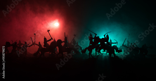 Medieval battle scene with cavalry and infantry. Silhouettes of figures as separate objects, fight between warriors on dark toned foggy background. Night scene.