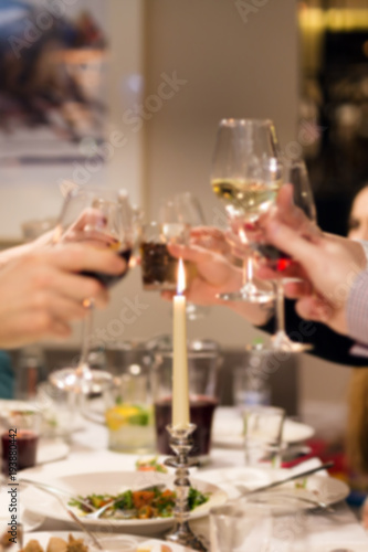 Blurred abstract background of clinking glasses of wine. Cheers after speech. Party at cafe or restaurant. Family celebration or anniversary