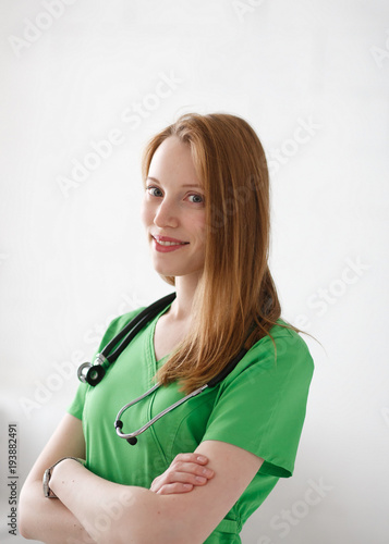 Portrait of friendly, smiling confident female doctor, healthcare professional with green lab coat. Natural light private clinic background photo