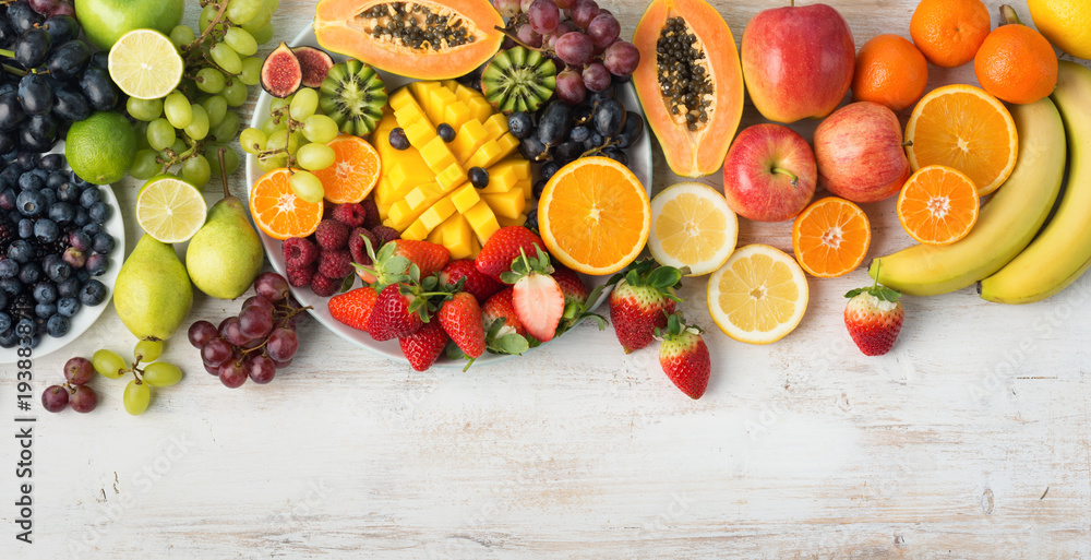 Naklejka Asortyment świeżych owoców i warzyw w kolorach tęczy na białym stole, widok z góry, selektywne focus