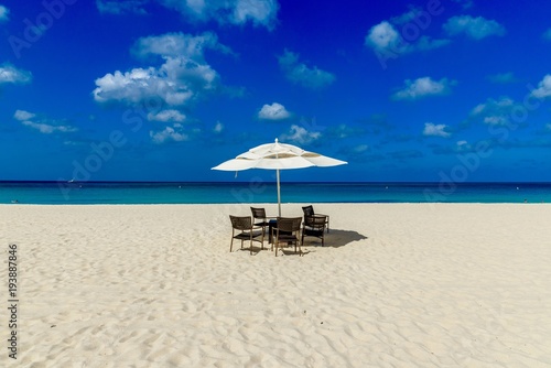 Idyllic caribbean landscape with table, chairs and a parasol in Aruba.