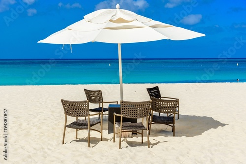 Idyllic caribbean landscape with table  chairs and a parasol in Aruba.