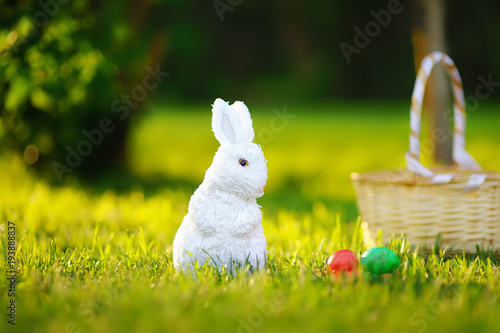 Colorful eggs and cute white toy bunny during egg hunt on Easter