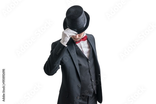 Gallant magician or illusionist in suit is taking off his hat. Isolated on white background.