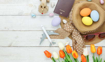 Table top view shot of decoration Happy Easter holiday background with accessory woman to travel concept.Flat lay bunny egg with tulip flower and rabbit doll on modern white wooden at office desk.