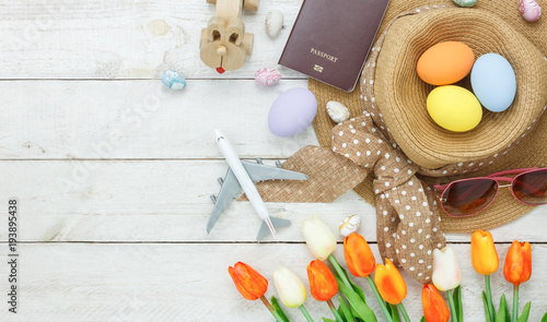 Table top view shot of decoration Happy Easter holiday background with accessory woman to travel concept.Flat lay bunny egg with tulip flower and rabbit doll on modern white wooden at office desk.