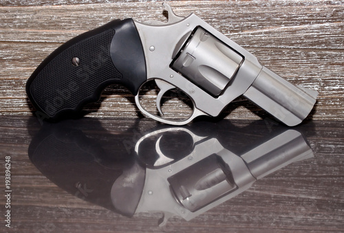 A stainless steel 44 special magnum revolver on a reflective surface with a wooden background photo