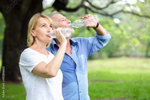 Portrait senior couple standing drinking water at the park