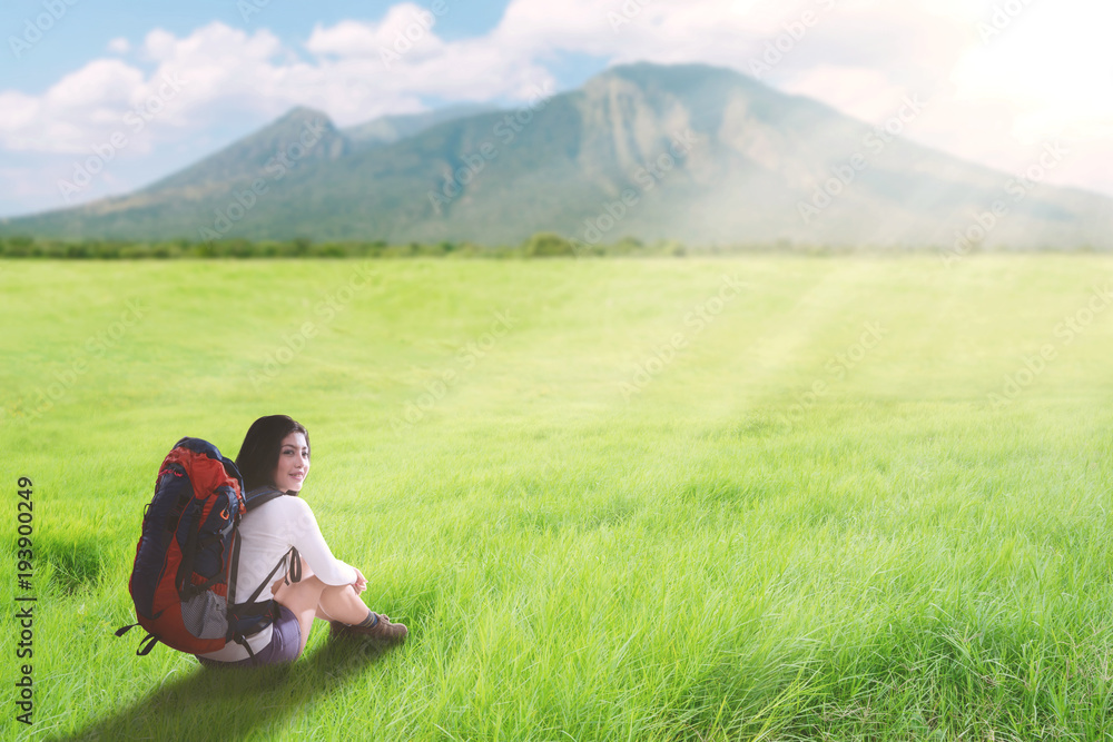 Asian tourist woman sitting on a greenery hill trail with backpack Asian tourist woman sitting on a greenery hill trail with backpack