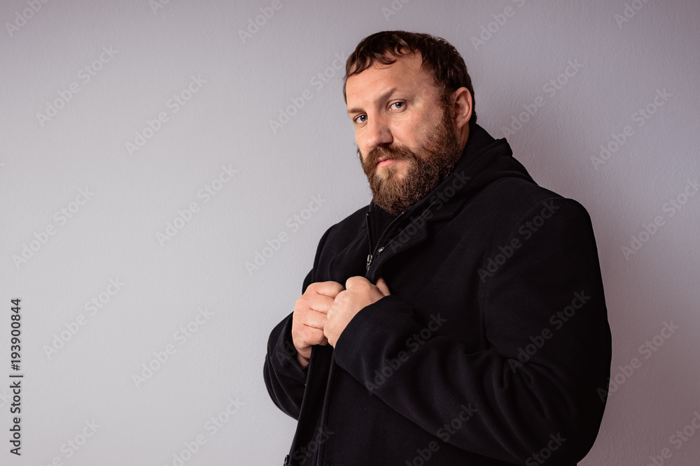 Fashion portrait handsome elegant bearded man wearing black coat against gray background wall. Fashion portrait handsome elegant bearded man wearing black coat against gray background wall.