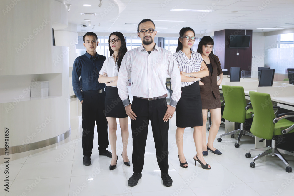 Confident manager standing with his team at office