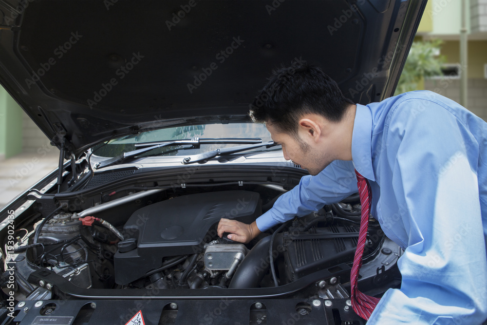 Asian businessman checking the engine of a damaged car Asian businessman checking the engine of a damaged car