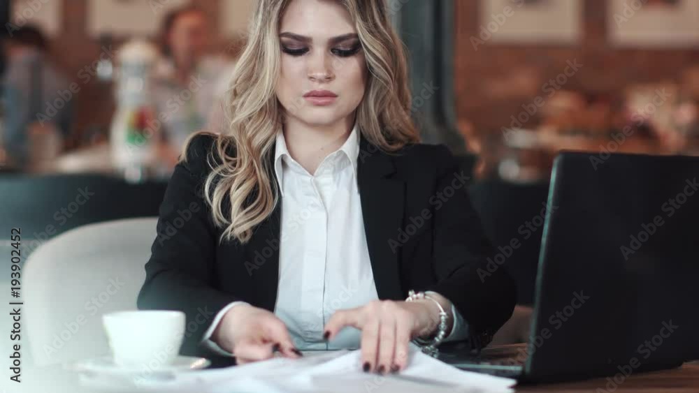 a young woman in business clothes working on a laptop sitting at a table in a cafe. business woman working in an informal setting a young woman in business clothes working on a laptop sitting at a table in a cafe. business woman working in an informal setting