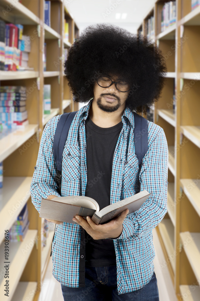 Afro male student reading a book at library Afro male student reading a book at library