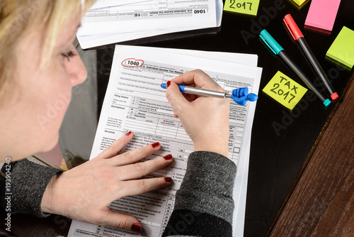 Woman fills the tax form, working with tax documents.  Form 1040 Individual Income Tax return form. United States Tax forms 2016/2017. photo