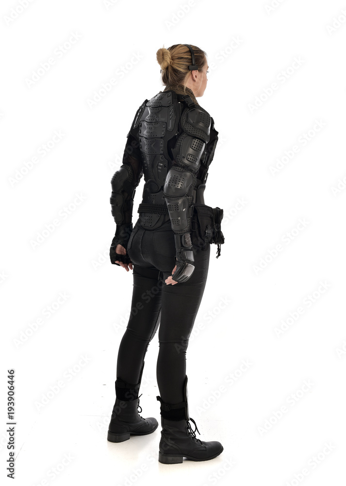 full length portrait of female soldier wearing black tactical armour facing away from camera, isolated on white studio background. full length portrait of female soldier wearing black tactical armour facing away from camera, isolated on white studio background.