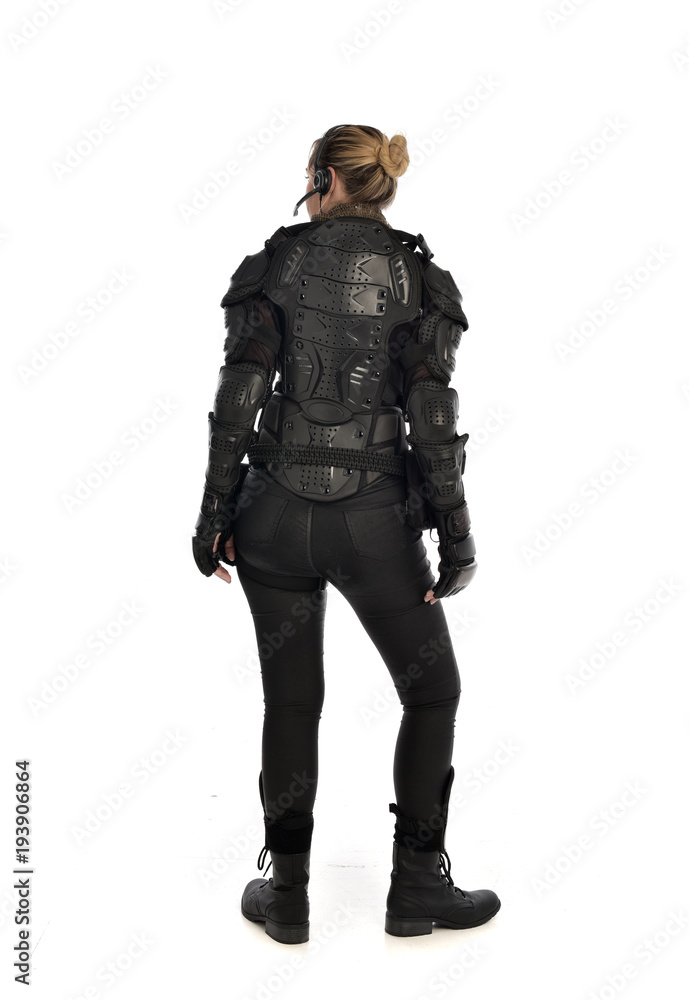 full length portrait of female soldier wearing black tactical armour facing away from camera, isolated on white studio background. full length portrait of female soldier wearing black tactical armour facing away from camera, isolated on white studio background.