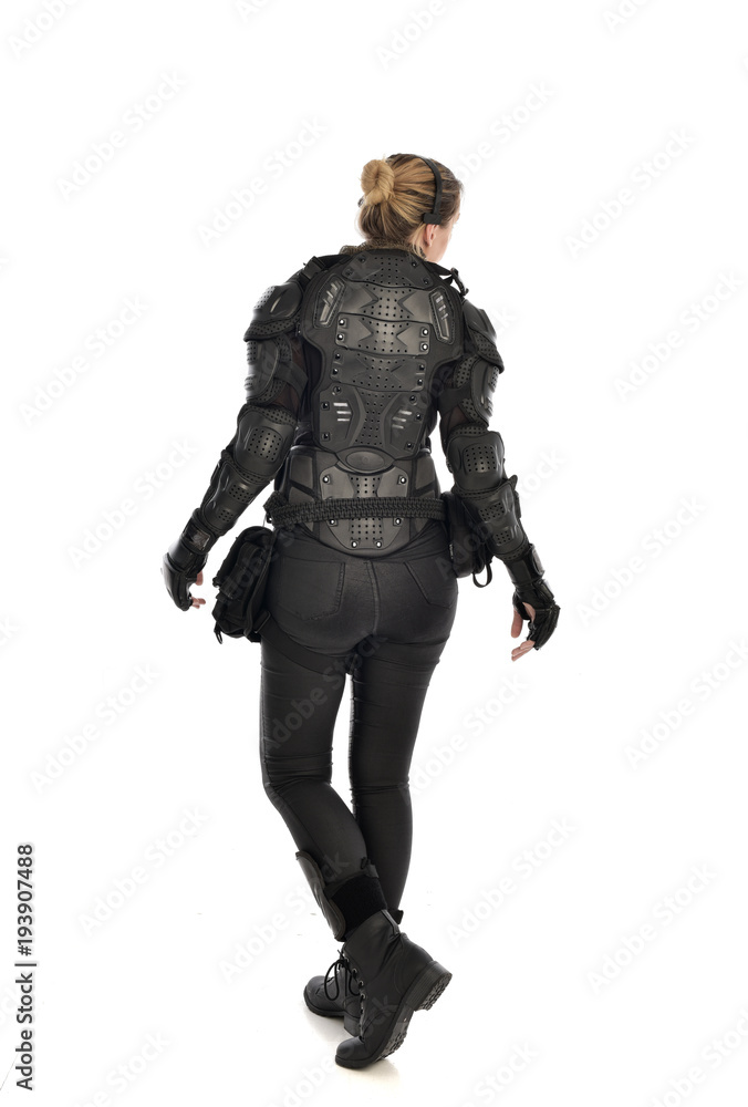 full length portrait of female soldier wearing black tactical armour facing away from camera, isolated on white studio background. full length portrait of female soldier wearing black tactical armour facing away from camera, isolated on white studio background.