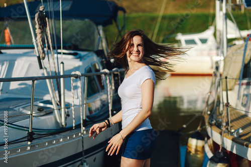 young beautiful girl is smiling at the camera on the background of summer yachts © Vladimir