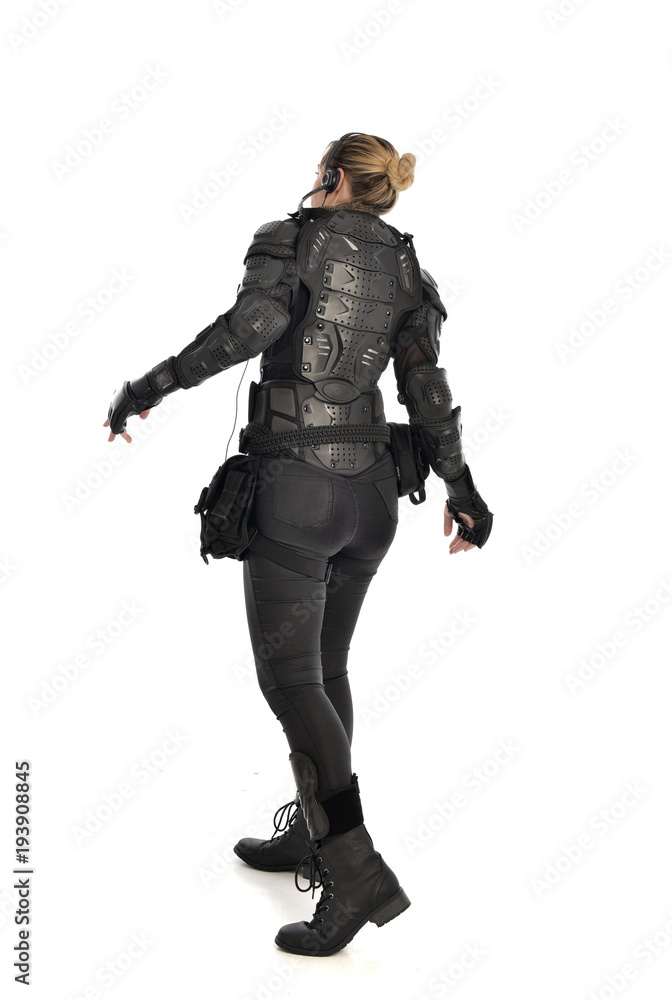 full length portrait of female soldier wearing black tactical armour facing away from camera, isolated on white studio background. full length portrait of female soldier wearing black tactical armour facing away from camera, isolated on white studio background.