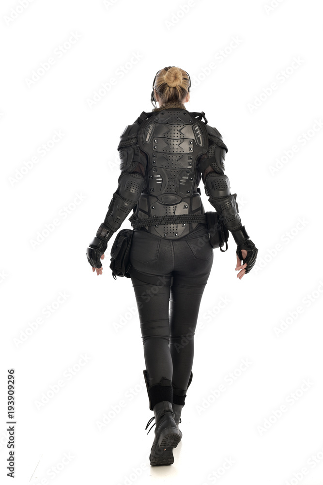full length portrait of female  soldier wearing black  tactical armour  facing away from camera, isolated on white studio background.