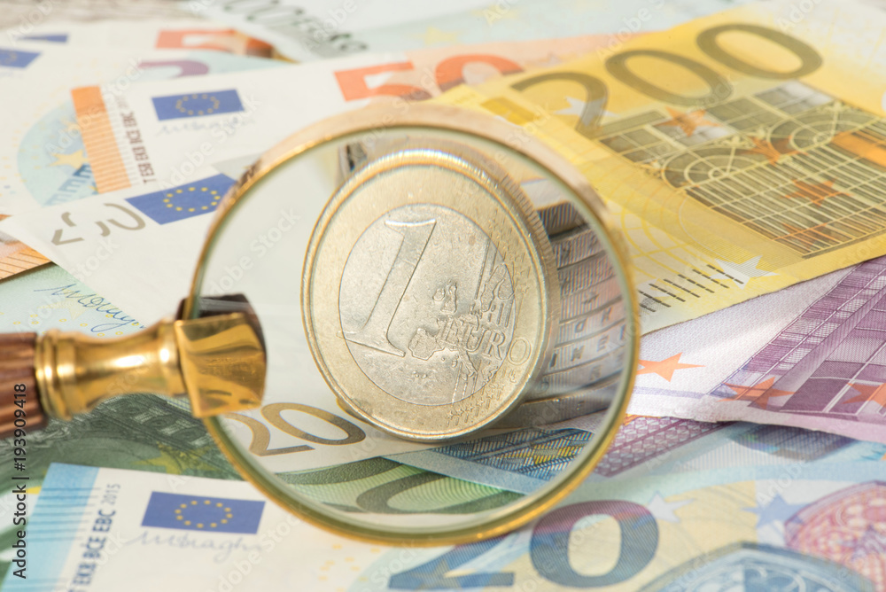 Eine Lupe, Euro Geldscheine und Euro Münzen Eine Lupe, Euro Geldscheine und Euro Münzen