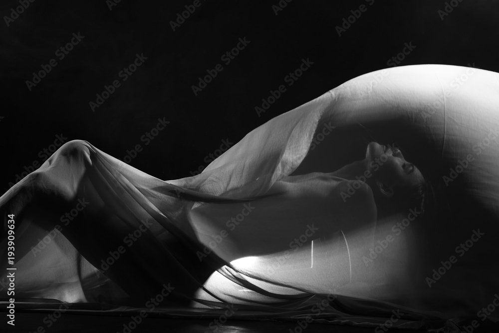 Fototapeta premium zmysłowy seksowny wygląd pięknej figury dziewczyny ukrytej w lekkiej cienkiej tkaninie, aby pokazać sylwetkę kobiecego ciała leżącego na podłodze