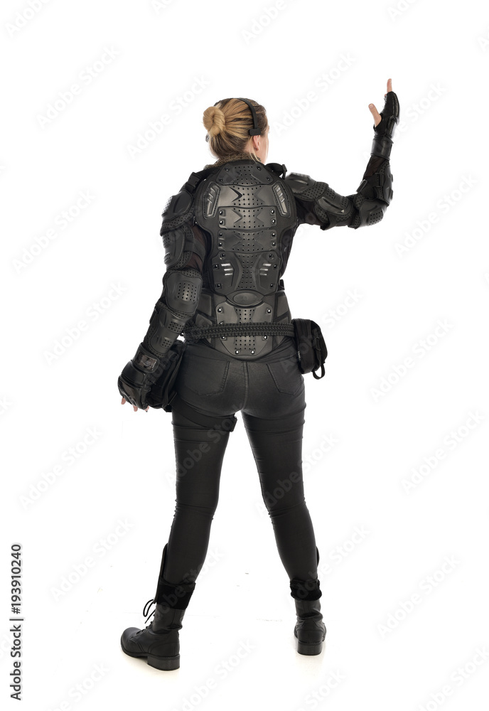 full length portrait of female soldier wearing black tactical armour facing away from camera, isolated on white studio background. full length portrait of female soldier wearing black tactical armour facing away from camera, isolated on white studio background.