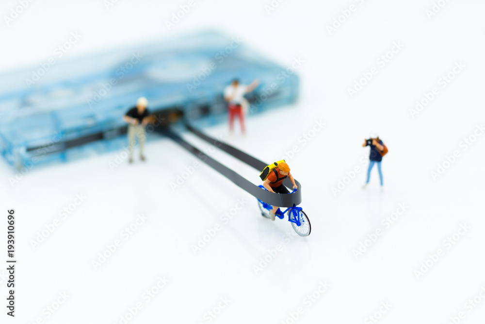 Fototapeta premium Miniature people: Man cycling to win on Compact Cassette. Image use for music , sport, business concept.