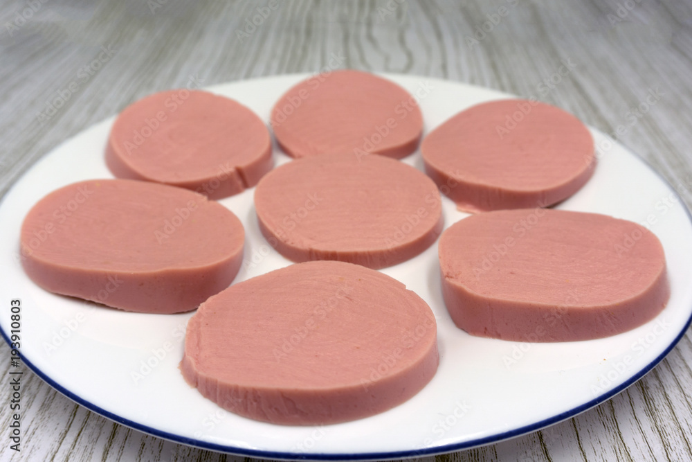 Three slices of boiled sausage with pieces of cucumber, a lettuce leaf, a ring of sweet pepper and garlic . Three slices of boiled sausage with pieces of cucumber, a lettuce leaf, a ring of sweet pepper and garlic .