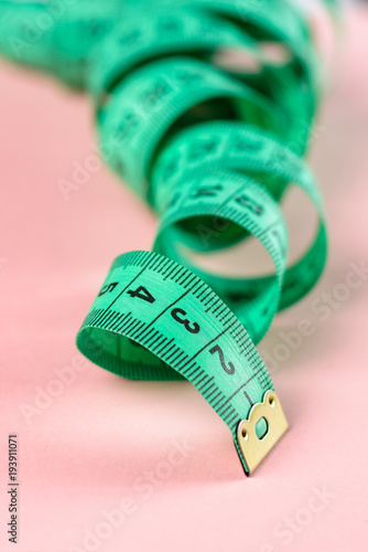 Measure Tape. Body measuring curly ruler sewing cloth Tailor soft tape on pink rose background.