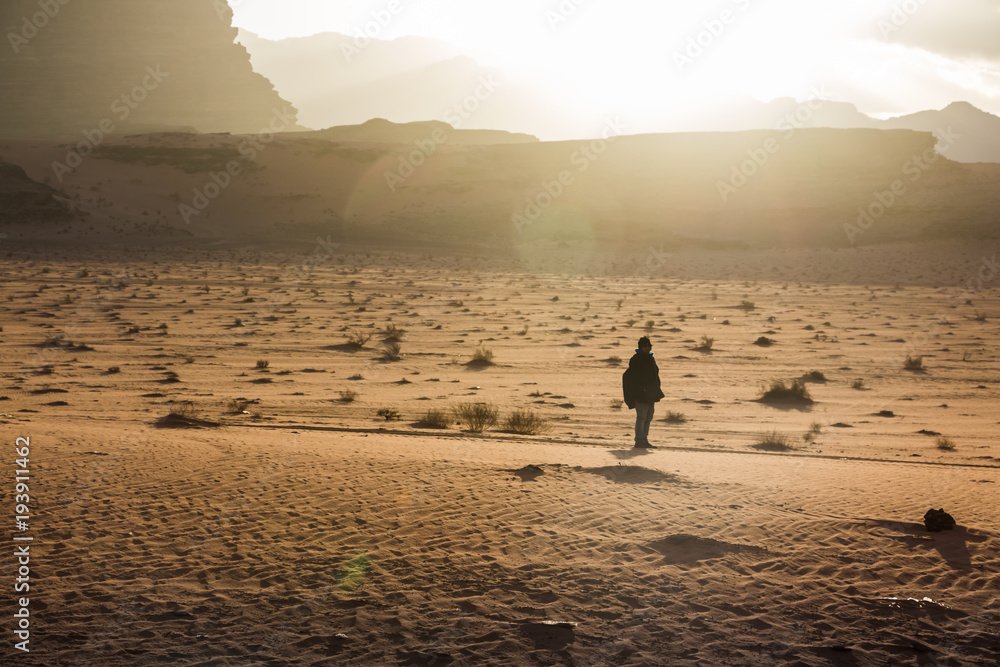 Obraz premium Silhouette of a girl who watches the sunset in desert in Jordan
