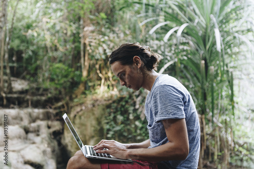 White man using computer laptop at waterfall